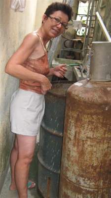 Juana junto al tanque de 55 galones que le llenó su hermano para que tuviera agua.